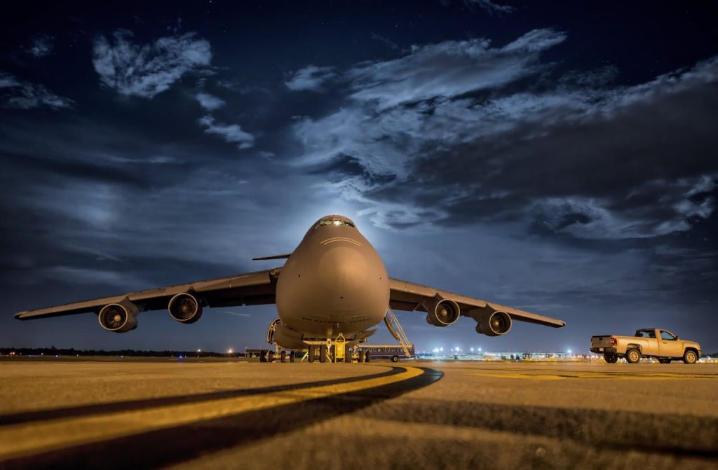 airplane-in-front-and-night-sky-67563 A large cargo plane stationed on the tarmac under the night sky, ready for transport.